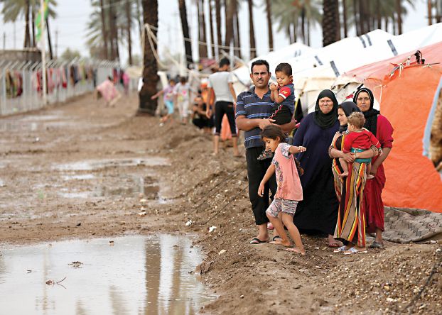 Internally displaced Iraqis stand outside their tents submerged in rainwater in at a refugee camp in Youssifiyah, 12 miles (20 kilometers) south of Baghdad, Iraq, Thursday, Oct. 29, 2015. Still, the burden is always hardest on those who have nothing. At a camp for displaced people in the town of Yousifiyya, the water was knee-high and pouring into tents, soaking mattresses and other belongings. Iraq is home to more than three million displaced Iraqis and Syrian refugees, many of whom are barely able to get by. (AP Photo/Hadi Mizban)