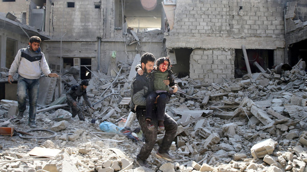 ATTENTION EDITORS - VISUAL COVERAGE OF SCENES OF INJURY OR DEATH A man carries an injured boy as he walks on rubble of damaged buildings in the rebel held besieged town of Hamouriyeh, eastern Ghouta, near Damascus, Syria February 21, 2018. REUTERS/Bassam Khabieh TEMPLATE OUT TPX IMAGES OF THE DAY