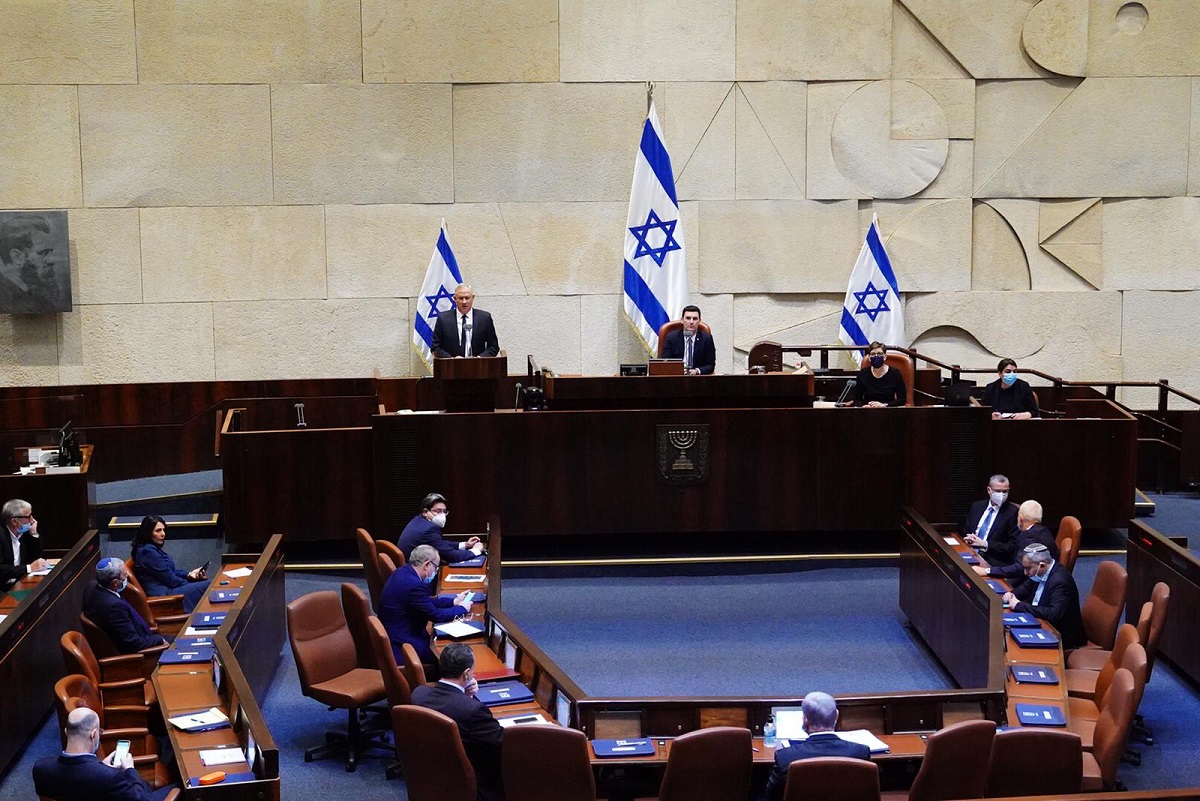 Benny Gantz, at podium, the centrist Blue and White party leader, and Israeli Prime Minister Benjamin Netanyahu's partner in the new unity government, speaks during a swearing in ceremony, at the Knesset, Israel's parliament, in Jerusalem, Sunday, May 17, 2020. Netanyahu is finally swearing in his new government after three deadlocked and divisive elections, a year and a half of political paralysis and another three-day delay because of political infighting in his Likud party over coveted Cabinet posts. Over the weekend, both Netanyahu and his rival-turned-partner Gantz announced their appointments for the new government — the most bloated in Israeli history. (Adina Valman/Knesset Spokespersons' Office via AP)